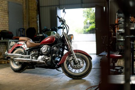Téléchargez les photos : Atelier de moto authentique une belle moto moderne se tient dans le garage avant réparation - en image libre de droit