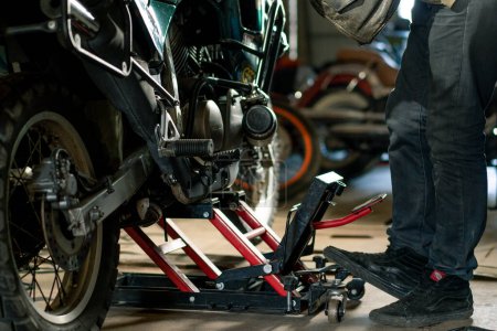 Photo for Creative authentic motorcycle workshop Garage biker mechanic repairs motorcycle jacks it up - Royalty Free Image