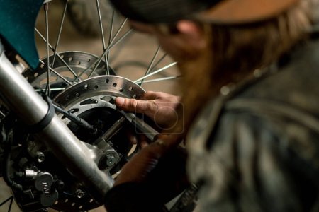 Téléchargez les photos : Atelier de moto authentique créatif Garage motard mécanicien roue réparatrice avec clé close-up - en image libre de droit