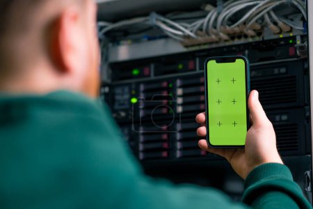Foto de Centro de datos de primer plano hacker o ingeniero que sostiene el teléfono con pantalla verde robando información de servidores tecnología de almacenamiento en la nube - Imagen libre de derechos