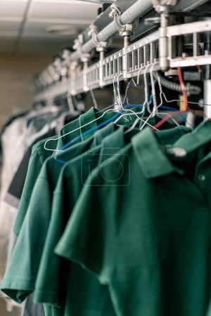 Photo for Industrial laundry in the hotel clean shirts of employees and guests sorted after washing hang on clotheslines concept cleanliness and hospitality - Royalty Free Image