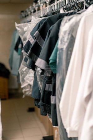 Foto de Lavandería industrial en el hotel camisas limpias de los empleados y los huéspedes ordenados después de lavar cuelgan de tendedero concepto limpieza y hospitalidad - Imagen libre de derechos