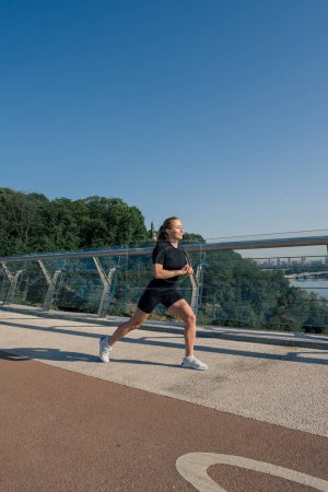 Foto de Chica deportista joven fitness por la mañana haciendo ejercicios de calentamiento de piernas antes de entrenar en la calle en la ciudad en el puente Salud deportiva - Imagen libre de derechos