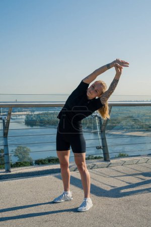 Téléchargez les photos : Fitness jeune fille sportive le matin faire des exercices d'échauffement avant de s'entraîner dans la rue dans la ville sur le pont Sport santé - en image libre de droit