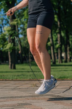 Foto de Chica deportista joven fitness en la mañana haciendo deportes saltar la cuerda durante el ejercicio al aire libre en la ciudad en el parque de salud primer plano de las piernas - Imagen libre de derechos