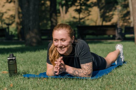 Téléchargez les photos : Portrait d'une jeune fille sportive allongée sur un tapis de sport se reposant à l'extérieur après s'être entraînée dans un parc concept de mode de vie sain - en image libre de droit