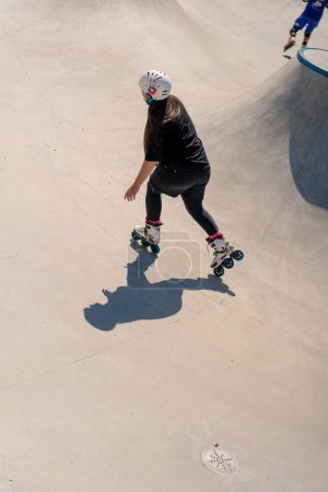 Photo for Young skilled woman rollerblading and jumping on the ramp in the skate park outside Practicing her tricks or technique of rollerblading competition - Royalty Free Image