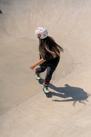 Foto de Joven mujer calificada patinaje y saltar en la rampa en el parque de skate fuera Practicando sus trucos o técnica de competencia patinaje - Imagen libre de derechos