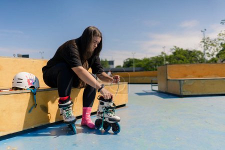 Photo for Young hipster girl wearing roller skates tying laces skate park before skating street extreme sport - Royalty Free Image