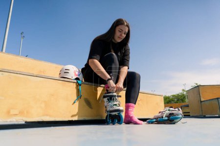 Photo for Young hipster girl wearing roller skates tying laces skate park before skating street extreme sport - Royalty Free Image
