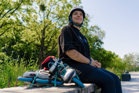 Téléchargez les photos : Portrait d'une jeune hipster souriante dans un skate park portant un casque de protection avant de commencer à patiner en arrière-plan - en image libre de droit