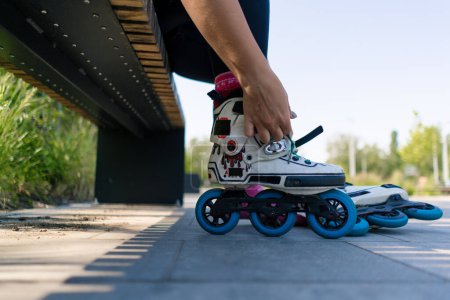 Photo for Young hipster girl puts on roller skates in skate park before starting skating street extreme sport closeup of legs - Royalty Free Image