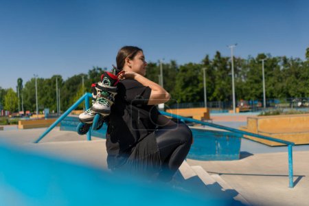 Téléchargez les photos : Jeune fille hipster assis dans un skate park avec des patins à roulettes avant de commencer la leçon d'entraînement sports terrain rue sports fermer - en image libre de droit