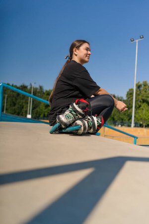 Photo for Young hipster girl sitting in skate park with roller skates before starting training lesson sports ground street sports close up - Royalty Free Image