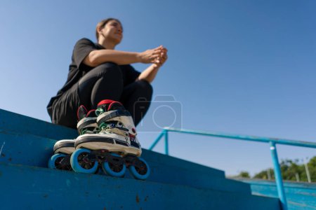 Photo for Young hipster girl sitting in skate park with roller skates before starting training lesson sports ground street sports close up - Royalty Free Image