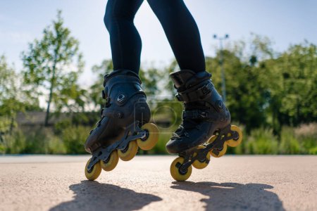 Photo for Sporty girl practicing tricks on roller skates in park city background enjoying roller skating lesson close up legs street sport - Royalty Free Image
