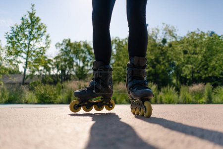 Photo for Sporty girl practicing tricks on roller skates in park city background enjoying roller skating lesson close up legs street sport - Royalty Free Image