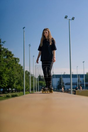 Téléchargez les photos : Fille sportive promenades patins à roulettes dans le parc sur fond de ville Fille active aime patiner à roulettes leçon rue sport concept - en image libre de droit