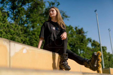Photo for Sporty girl after rollerblading rests on the sports ground thoughtful happy with the street sports lesson - Royalty Free Image