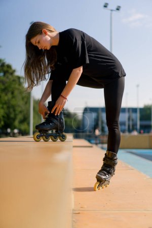 Photo for Young beautiful girl in park tying laces on roller skate before skating workout active lifestyle hobby - Royalty Free Image