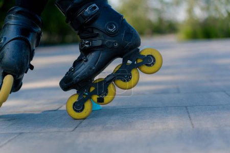 Téléchargez les photos : Fille sportive pratiquant des tours sur patins à roulettes dans le parc sur fond de ville profiter de la leçon de patinage à roulettes avec jetons gros plan Street concept de sport - en image libre de droit