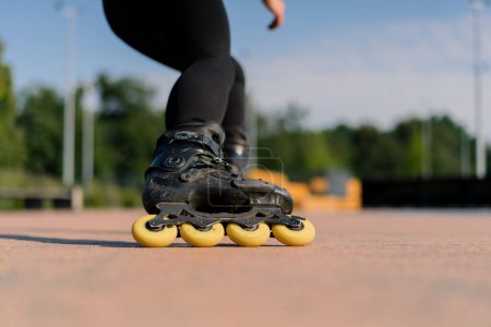 Photo for Sporty girl practicing tricks on roller skates in park on city background enjoying roller skating lesson with chips closeup Street sports concept - Royalty Free Image