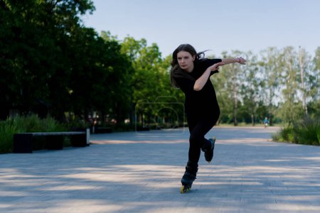 Téléchargez les photos : Fille sportive promenades patins à roulettes dans le parc sur fond de ville Fille active aime patiner à roulettes leçon rue sport concept - en image libre de droit