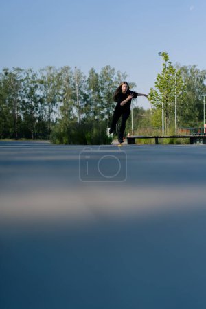 Foto de Chica deportiva paseos patines en el parque en el fondo de la ciudad chica activa en disfruta de patinaje lección calle concepto de deportes de calle - Imagen libre de derechos
