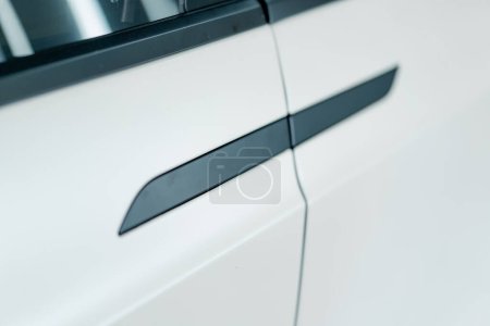Photo for The door of luxury white electric car with black handles at a car service during car detailing and dry cleaning - Royalty Free Image