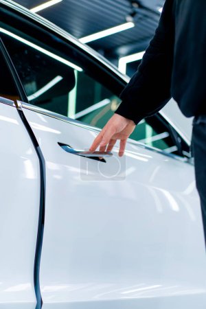 Photo for A man opens the door of his luxury white car after detailing and dry cleaning at car service - Royalty Free Image