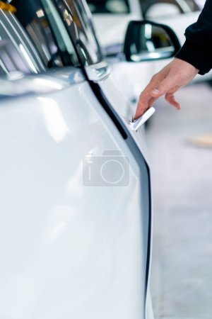 Foto de Un hombre abre la puerta de su lujoso coche blanco después de detallar y limpiar en seco en el servicio de automóviles - Imagen libre de derechos