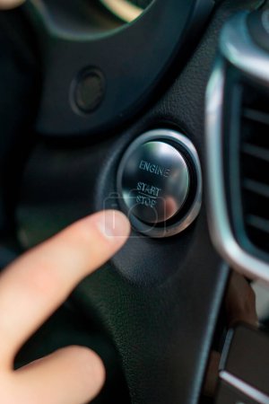 Photo for Man presses the start button of his luxury car black car interior - Royalty Free Image
