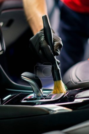 Téléchargez les photos : Un employé de lavage de voiture nettoie soigneusement l'intérieur d'une voiture de luxe avec un chiffon un aspirateur à brosse vapeur détaillant en gros plan - en image libre de droit