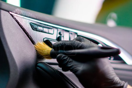 Foto de Un trabajador de lavado de coches limpia cuidadosamente el interior de un coche de lujo con un trapo una aspiradora de cepillo vapor detallando de cerca - Imagen libre de derechos