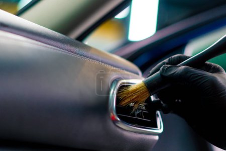 Téléchargez les photos : Un employé de lavage de voiture nettoie soigneusement l'intérieur d'une voiture de luxe avec un chiffon un aspirateur à brosse vapeur détaillant en gros plan - en image libre de droit