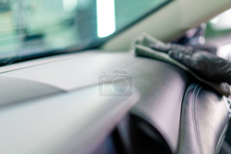 Foto de Detallar a un hombre un empleado de una estación de servicio de automóviles realiza limpieza química y lavado de un coche con tela de microfibra - Imagen libre de derechos