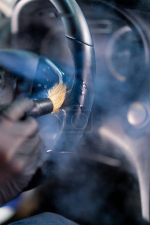 Photo for A car wash worker carefully cleans the interior of a luxury car with a rag a brush vacuum cleaner steamer detailing - Royalty Free Image