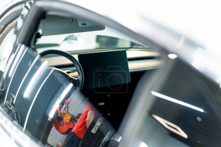 Foto de Primer plano de la pantalla multimedia de un coche blanco de lujo con interior negro después de la limpieza en seco y la vista de lavado a través de la ventana trasera - Imagen libre de derechos