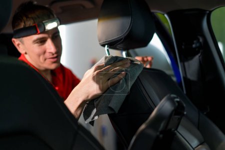 Photo for Detailing a man an employee of a car service station performs chemical cleaning and washing of a car with microfiber cloth - Royalty Free Image