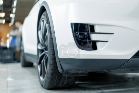 Téléchargez les photos : Détail pare-chocs et roue d'une voiture de luxe blanche après le lavage à la station-service de voiture - en image libre de droit