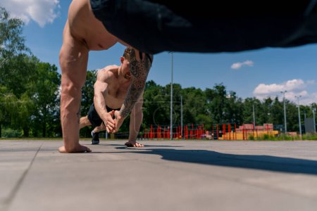 Téléchargez les photos : Entraîneur et jeune sportif faisant push-ups dans la rue et se donnant un cinq élevé pendant l'entraînement bras d'exercice épaules beau corps sexy - en image libre de droit