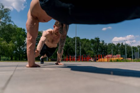 Téléchargez les photos : Entraîneur et jeune sportif faisant push-ups dans la rue et se donnant un cinq élevé pendant l'entraînement bras d'exercice épaules beau corps sexy - en image libre de droit