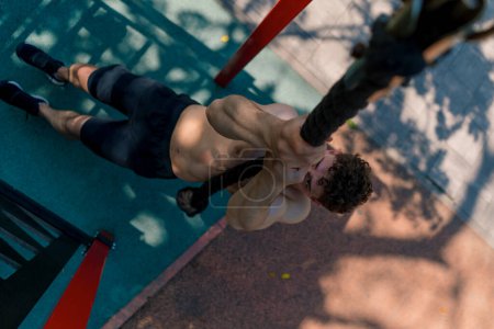 Foto de Joven deportista con un torso desnudo tira hacia arriba en una cuerda durante el entrenamiento al aire libre en el campo de deportes sexy bombeado cuerpo - Imagen libre de derechos