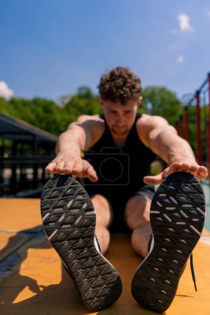Foto de Joven musculoso deportista culturista haciendo ejercicios abdominales durante la calle entrenamiento deportes primer plano - Imagen libre de derechos