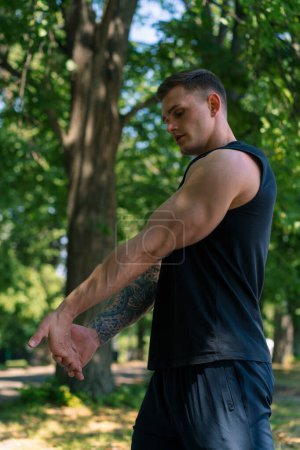 Téléchargez les photos : Portrait d'un jeune sportif tatoué faisant des exercices d'échauffement en plein air entraînement de rue dans la motivation du parc - en image libre de droit