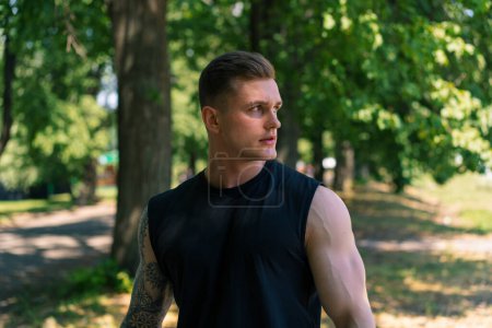 Foto de Retrato de joven deportista sudoroso con tatuajes y piercings mirando al aire libre pensativo entrenamiento al aire libre en la motivación del parque - Imagen libre de derechos
