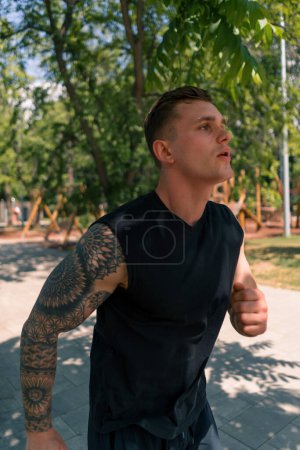 Photo for Portrait young exhausted tattooed runner in sportswear running in urban city park outdoor sports activity - Royalty Free Image