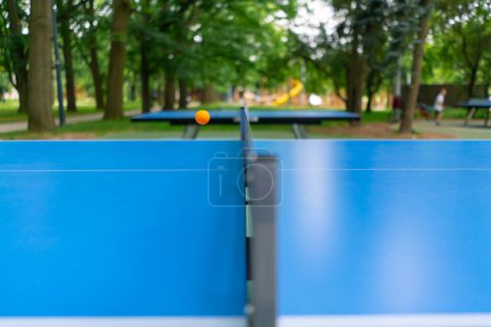 Foto de Primer plano de una pelota de ping-pong volando sobre la red en una mesa de tenis en el parque de la ciudad - Imagen libre de derechos