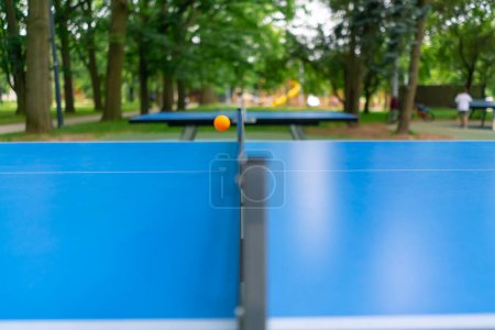 Foto de Primer plano de una pelota de ping-pong volando sobre la red en una mesa de tenis en el parque de la ciudad - Imagen libre de derechos