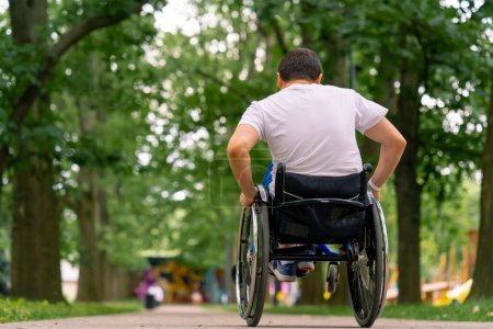 Foto de Inclusividad Un hombre con discapacidad hace acrobacias en silla de ruedas en un parque de la ciudad contra el telón de fondo de los árboles - Imagen libre de derechos